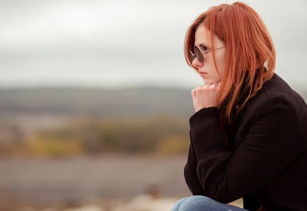 Atractiva, dolorosa, problemática, infeliz, joven con gafas, gafas de sol, pensar, mirar, ver, dolor, tristeza, depresión, lágrimas, llorando, ocultar, lágrimas de dolor, pérdida, dolor. Pelirroja, deprimida, hermosa chica, modelo sentado en la naturaleza en las colinas con vista perfecta, ojos redondos . —  Fotos de Stock