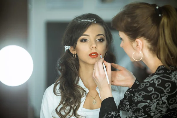 Professional master,makeup artist does cute,fashion,creative make-up,makes up eyes,lips.Beautiful,fashionable,glamorous,famous,nice,attractive,pretty,sexy celebrity,model,lady,girl,woman prepare for shooting.Nice face,pure,clean skin.Cosmetics.Salon,