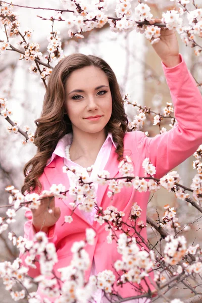 Muchacha muy hermosa en los árboles que florecen en el jardín de primavera.Tiempo de pring. Muy bonita, impresionante, hermosa, chica agradable con peinado perfecto, chaqueta rosa en el parque de flores de primavera con muchas flores blancas.Lindo . — Foto de Stock