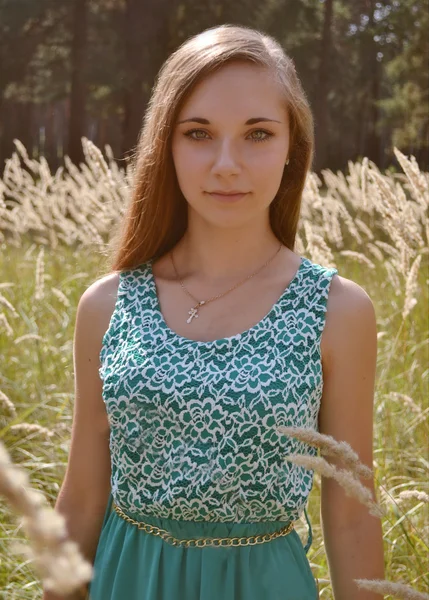 Menina bonita, agradável, bonita com olhos verdes, rosto bonito, cabelos longos em pé ensolarado, campo amarelo com orelhas, sibilos, culturas no dia de verão.Alegre, ensolarado, atraente, bonito, menina agradável no fiel ensolarado no verão . — Fotografia de Stock