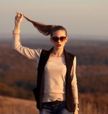 Glamorous, fashionable, strict, slender girl with sunglasses holds a tail in hand.