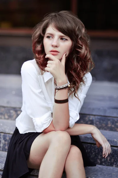 Depressed,unhappy,troubled,worried school girl think about good education.Young beautiful schoolgirl, student sits on a ladder.Very tired,depressed,thinking,worrying,melancholy,troubling school girl,student,girl sit near the school,campus,university — Stock Photo, Image