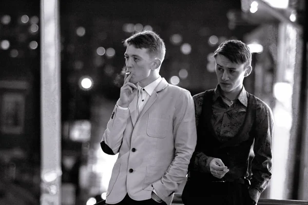 Two fashionable stylish james bond on streets, american, african. Two serious, powerful smoking angry gangsters stand in night city outdoors and wait for college.Two men in retro style — Stock Photo, Image