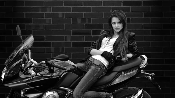 Séduisante fille se trouve sur le vélo sur fond noir avec veste en cuir.Cool, belle fille avec coiffure parfaite et maquillage avec moto, bike.Biker.Seductive fille se trouve sur le vélo sur fond noir . — Photo