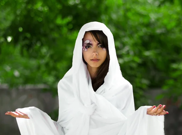 Portrait de fille sérieuse, sûre d'elle, puissante et confiante en robe blanc.Modèle à la mode, fille, femme en robe longue blanche avec un maquillage parfait et créatif avec les bras ouverts gracieux, les mains et les yeux noirs et noirs . — Photo