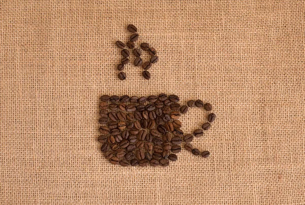 Coffee cup image made up of coffee beans on burlap background — Stock Photo, Image