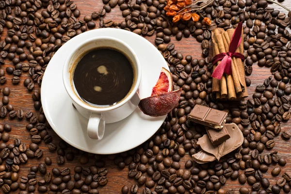 Latar belakang biji kopi dengan cangkir kofee, kayu manis, dan coklat — Stok Foto