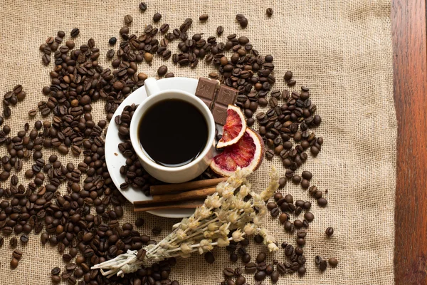 Cangkir kopi dengan kacang mentah di burlap — Stok Foto