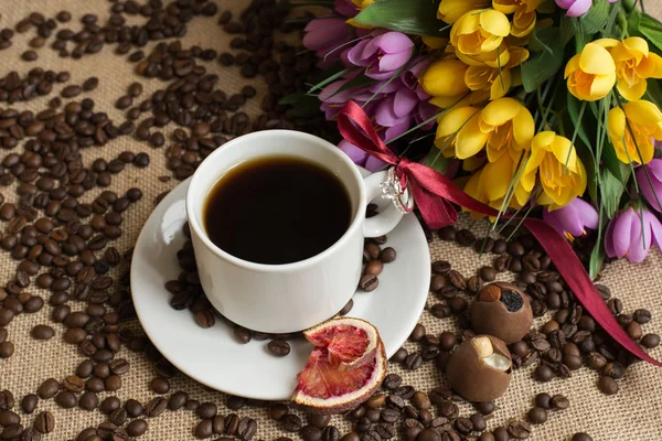 Kubek kawy z surowe ziarna na płótnie z kwiatem — Zdjęcie stockowe