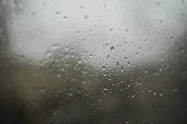 Gotas de lluvia en ventana borrosa, día lluvioso — Foto de Stock