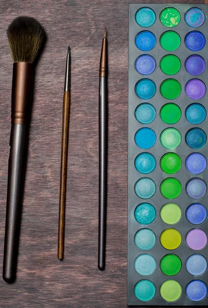 Set of brushes and eye shadow on wood background