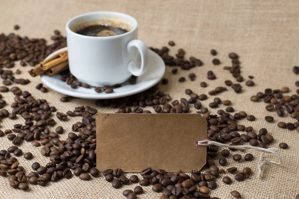 Чашка кофе с кофейными зёрнами и этикеткой — стоковое фото