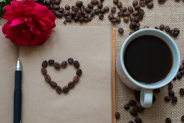 Beyaz fincan kahve, kahve çekirdekleri ve sketchbook ile