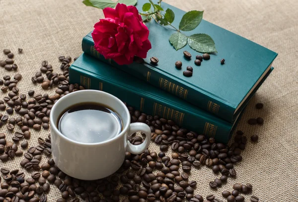 Taza de café blanco, con granos de café sobre fondo de libros — Foto de Stock