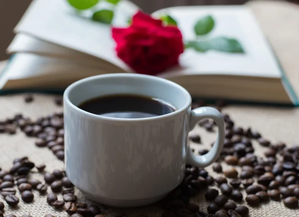 Taza de café blanco, con granos de café sobre fondo de libros — Foto de Stock