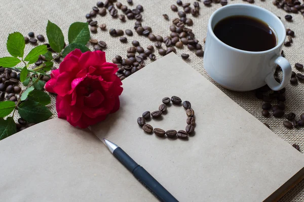 Taza de café blanco, con granos de café y cuaderno de bocetos — Foto de Stock