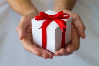 Beyaz hediye kutu kırmızı kurdele ile holding adam eller