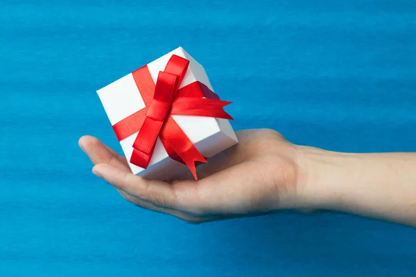 De handen van de man met witte geschenkdoos met rood lint — Stockfoto