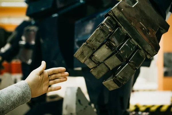 Close-up of a girl pulls her hand to the arm of the robot. Technology and the concept of the future of humanity. Bionic human artificial intelligence