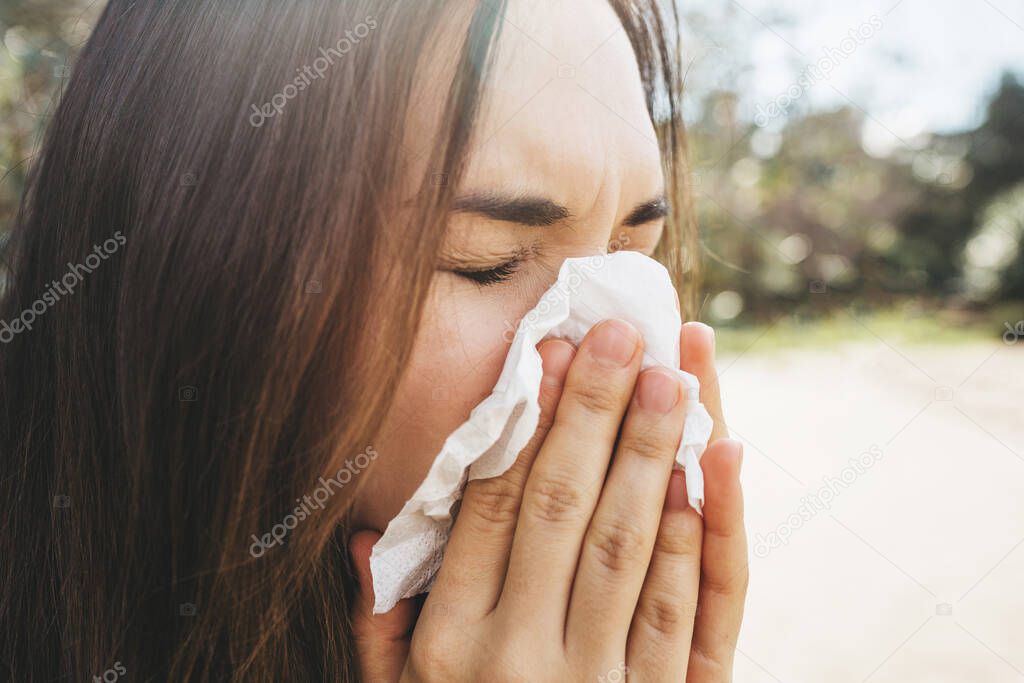 The woman blows her nose into a handkerchief. A symptom of an illness or allergy