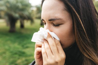 Kadın burnunu bir mendile sümkürdü. Bir hastalık veya alerji belirtisi.