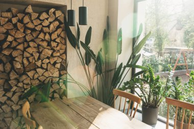 Kırsal bölge. Pencerenin yanındaki ev bitkileri ve yakacak odunlar. Tahta masa..