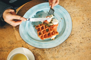 Yakın plan. Kadın kahvaltıda Belçika waffle 'ı yiyor.