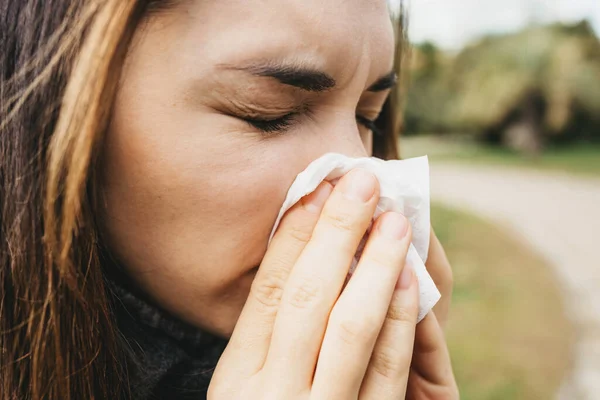 The woman blows her nose into a handkerchief. A symptom of an illness or allergy