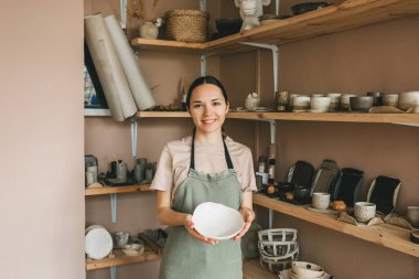 Kadın mağazada el yapımı çömlek satıyor..