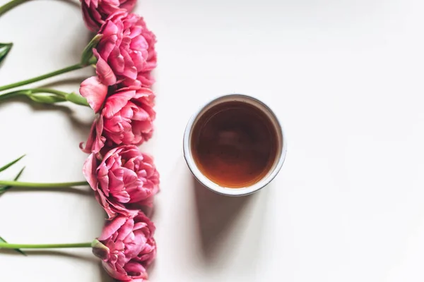 Eine Tasse Kaffee oder Tee auf weißem Hintergrund mit rosa Tulpen lizenzfreie Stockbilder