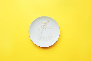 Sarı arka planda kırıntıları olan boş tabak.