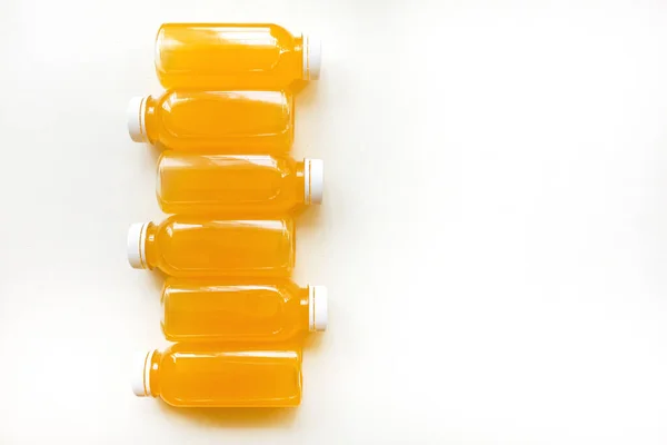 Butelki świeżo wyciśniętego soku pomarańczowego na białym tle. Płaskie ułożenie, widok z góry — Zdjęcie stockowe