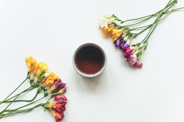 Secangkir kopi atau teh dengan latar belakang putih dengan warna-warni freesias — Stok Foto
