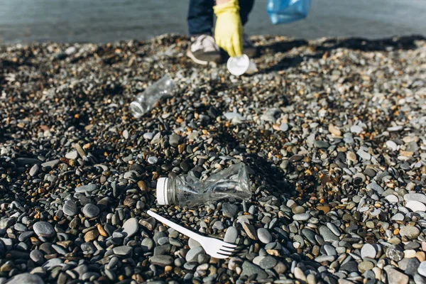 Egy önkéntes ember szemetet gyűjt egy koszos parton. A hulladék-újrafeldolgozás és a környezettisztítás fogalma — Stock Fotó