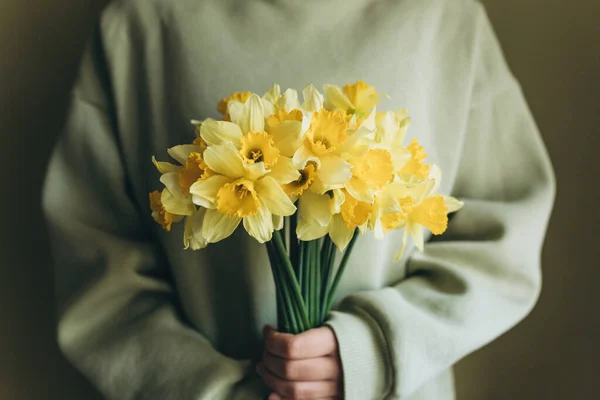 La mujer sostiene un ramo de narcisos amarillos en sus manos. — Foto de Stock