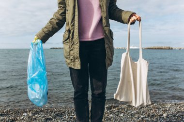 The woman chooses: plastic bags or multifunctional bags. The concept of zero waste and a conscious lifestyle.