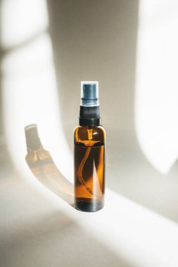 Beyaz arka planda koyu kehribar camından yapılmış bir kozmetik şişesi..