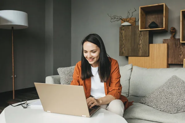 Una hermosa joven europea usando un ordenador portátil para el trabajo remoto desde casa. — Foto de Stock