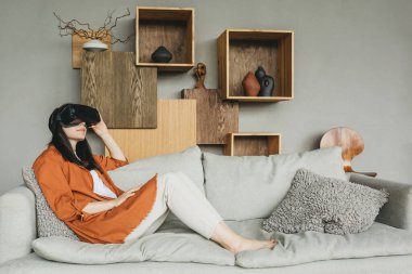 Sanal gerçeklik gözlüğü takan genç bir kadın, bir kulaklık, bir VR kutusu. Kız sanal gerçeklikteki nesnelere dokunmaya çalışıyor..