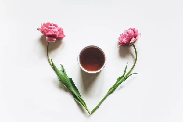 Šálek kávy nebo čaje na bílém pozadí s růžovými tulipány — Stock fotografie