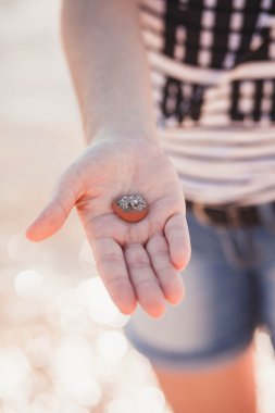 güzel kız sahilde elinde bir taş tutar