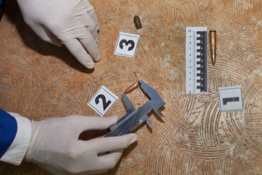 Expert examines a bullet at the crime scene clipart