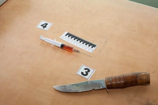 Una jeringa con sangre y un cuchillo en la escena del crimen — Foto de Stock