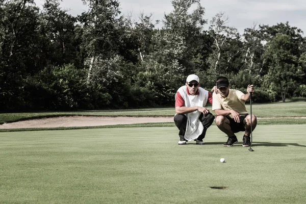 Golfare och caddy behandlingen grön — Stockfoto