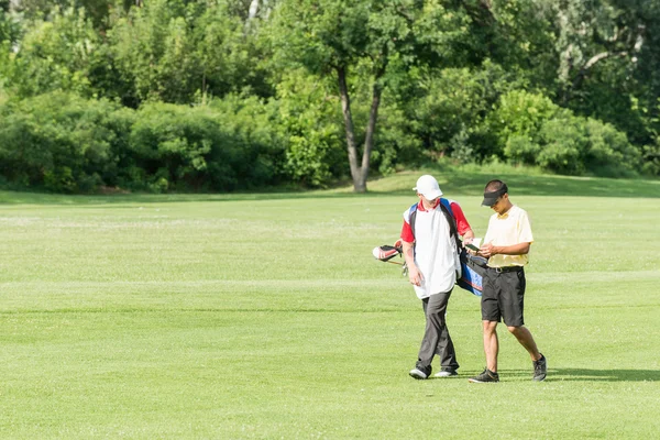 Golfista e caddy em um campo de golfe — Fotografia de Stock