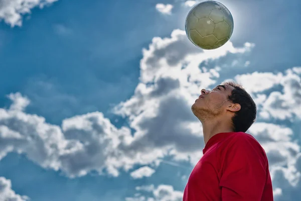 Jogador de futebol saltando a bola — Fotografia de Stock