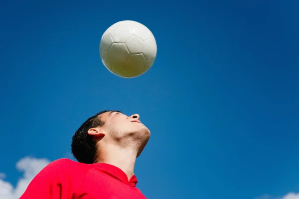 Футболист, прыгающий мяч — стоковое фото