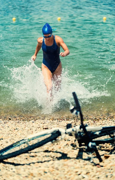 Atleta feminina correndo para fora da água — Fotografia de Stock
