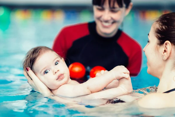 Baby boy in pool with mother and instructor — Stock Photo, Image