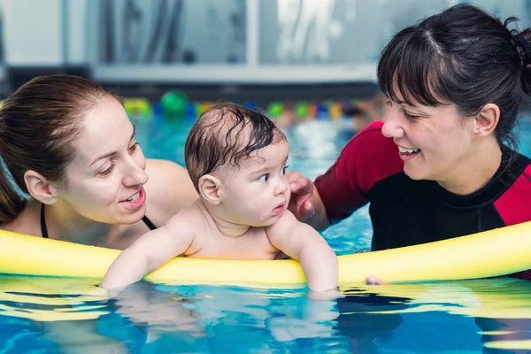 Baby boy with mother and instructor in pool — Stock Photo, Image